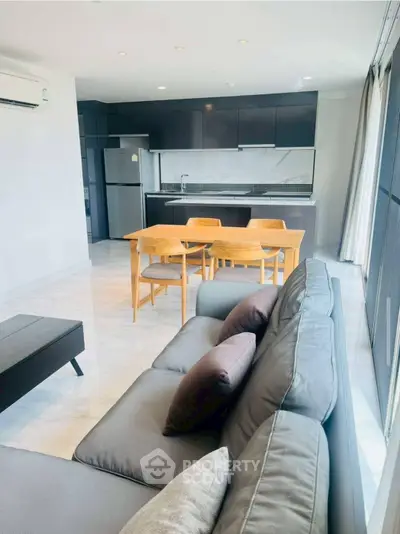 Modern open-layout living room and kitchen with sleek furniture and appliances.