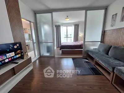 Modern studio apartment with sleek design, featuring a cozy living area and a stylish bedroom separated by sliding glass doors.