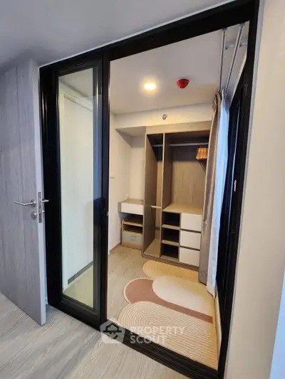Modern walk-in closet with sliding glass doors and stylish storage solutions.