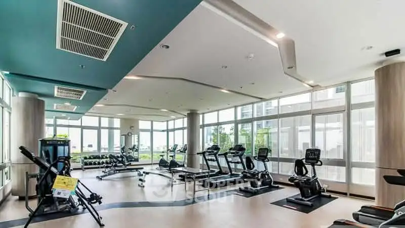 Spacious modern gym with state-of-the-art equipment and large windows for natural light.