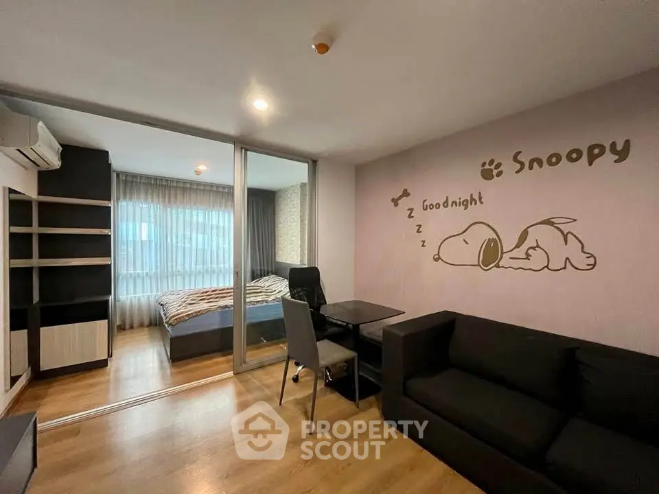 Cozy living room with Snoopy wall art and view into modern bedroom