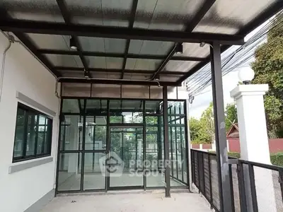 Modern building entrance with glass doors and covered patio, ideal for commercial or residential use.