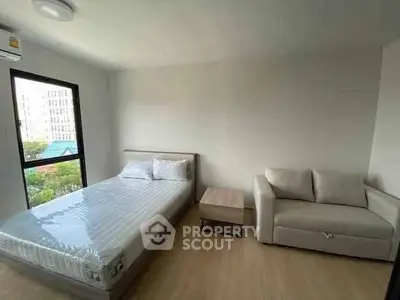 Spacious bedroom with natural light, featuring a comfortable bed and cozy sofa, ideal for relaxation.