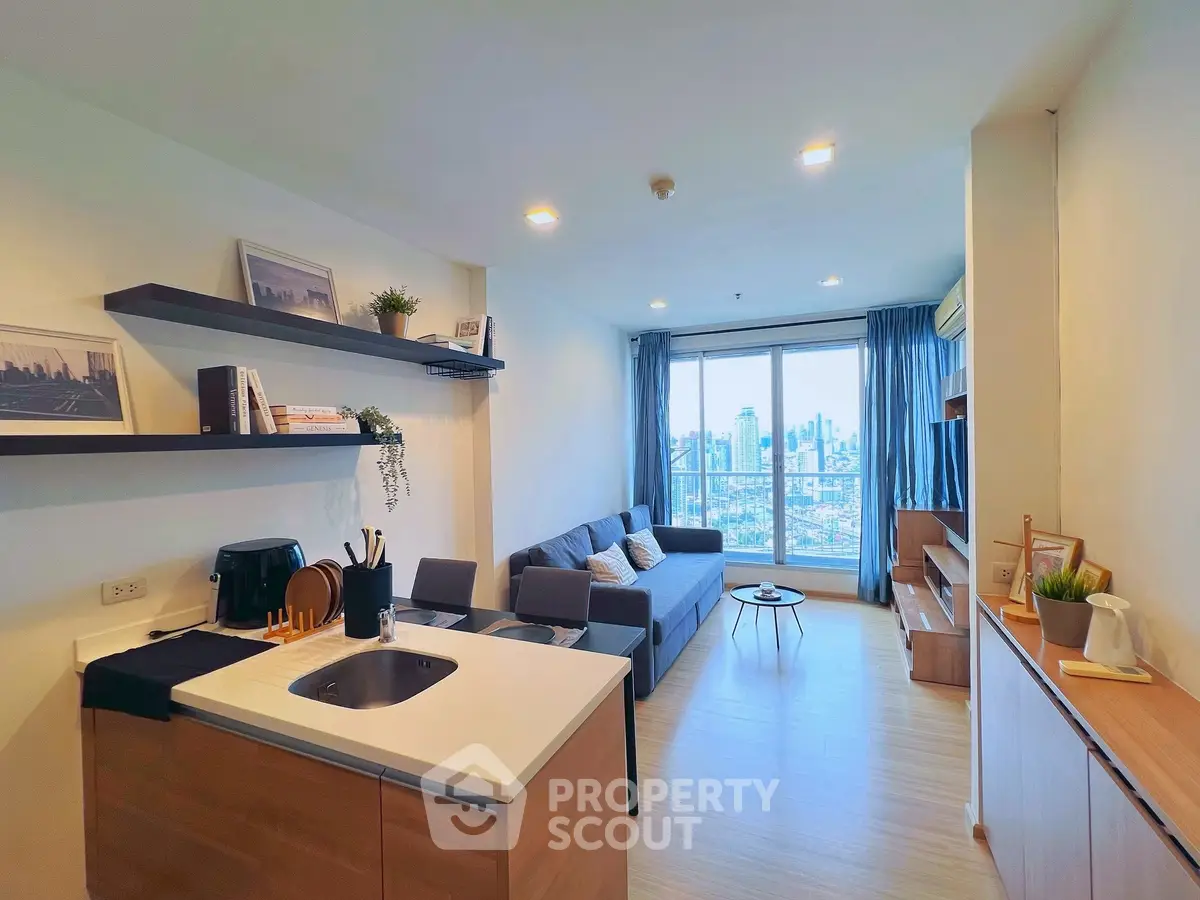 Modern living room with open kitchen and city view, featuring sleek furniture and stylish decor.
