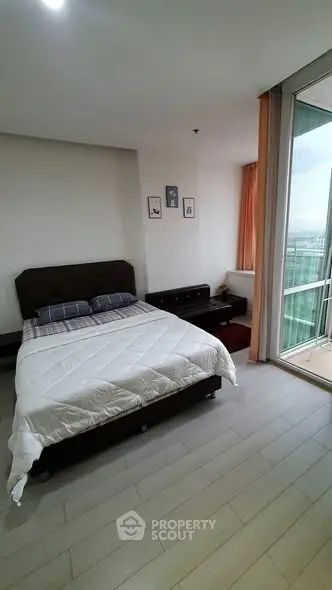 Spacious bedroom with modern decor and balcony view in a high-rise apartment.