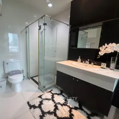 Modern bathroom with glass shower and stylish vanity in sleek design.