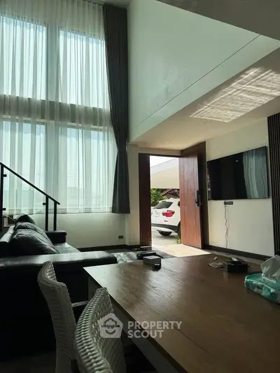 Spacious modern living room with high ceilings and natural light, featuring a sleek open layout and stylish decor.