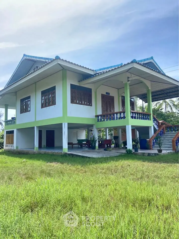 Charming elevated house with spacious veranda and lush green surroundings.