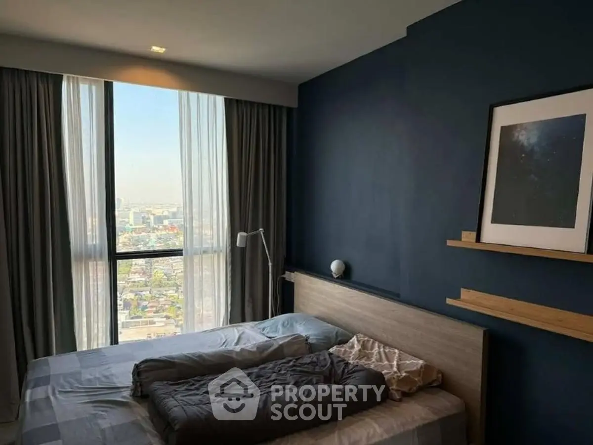 Modern bedroom with city view, featuring stylish decor and large window for natural light.