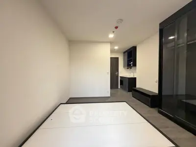 Modern minimalist studio apartment with sleek kitchen and ample storage space.