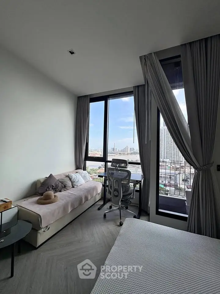 Modern bedroom with large windows and city view, featuring a cozy bed and stylish desk setup.