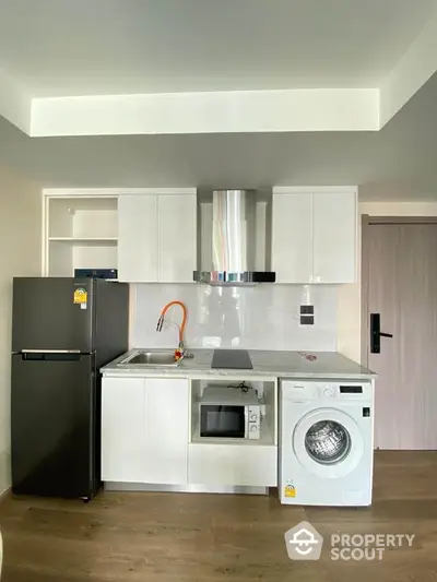 Modern kitchen with sleek appliances including washing machine and oven, ideal for compact living spaces.