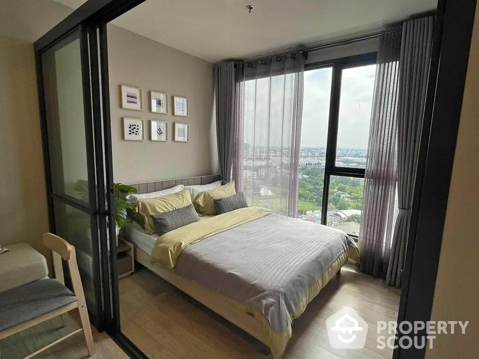 Modern bedroom with large windows offering stunning city views and elegant decor.