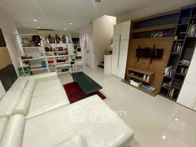 Spacious modern living room with sleek white furniture and built-in shelving, perfect for stylish urban living.