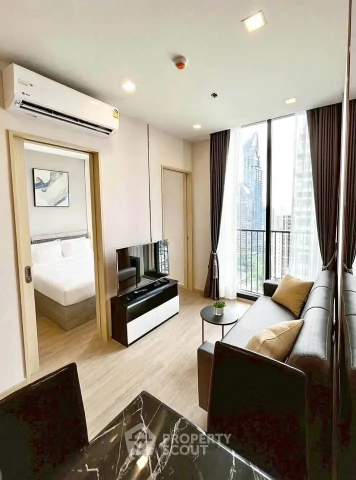 Modern living room with city view, featuring sleek furniture and natural light.