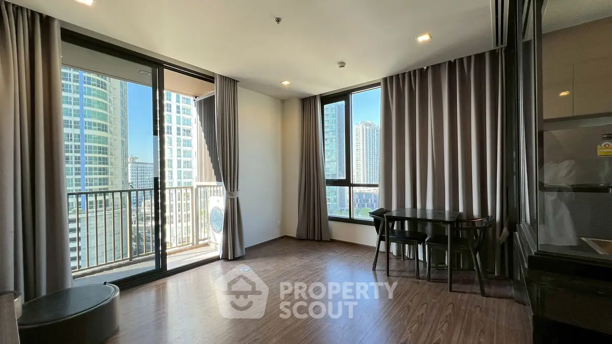 Modern living room with large windows and city view, featuring elegant dining area and balcony access.