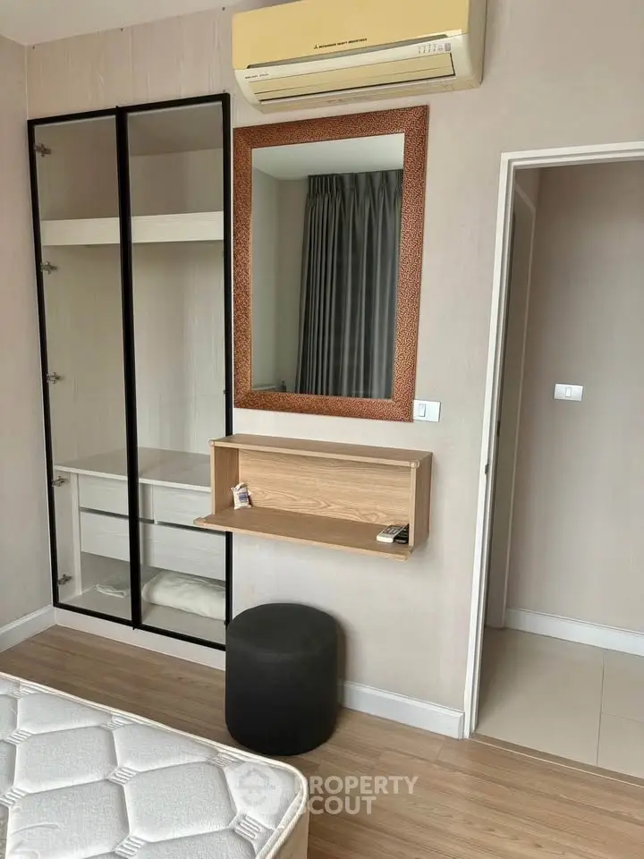 Modern bedroom with built-in wardrobe, air conditioning, and stylish mirror in a cozy apartment.