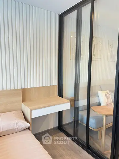 Modern bedroom with sliding glass partition and cozy living area