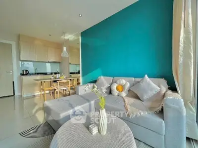 Modern living room with stylish decor and open kitchen layout, featuring a cozy gray sofa and vibrant teal accent wall.