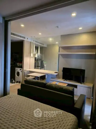 Modern studio apartment with open layout, featuring a cozy living area, dining space, and in-unit washing machine.