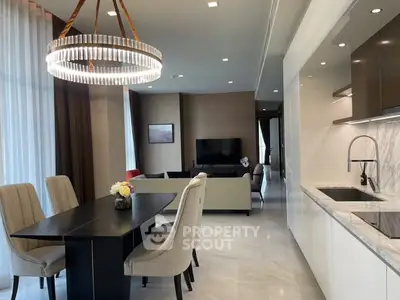 Luxurious open-plan living and dining area with elegant chandelier and modern kitchen.
