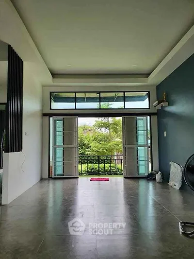 Spacious living room with large windows and garden view, perfect for natural light lovers.