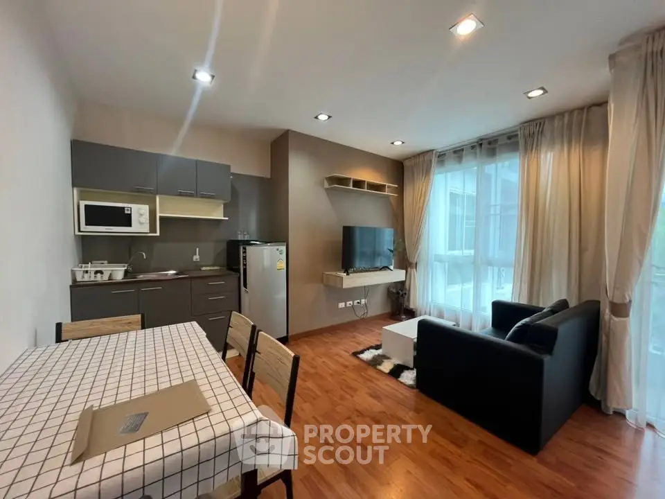 Modern living room with open kitchen, featuring sleek furniture and large windows for natural light.