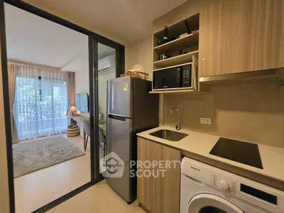 Modern kitchen with sleek appliances and open layout leading to cozy living room.