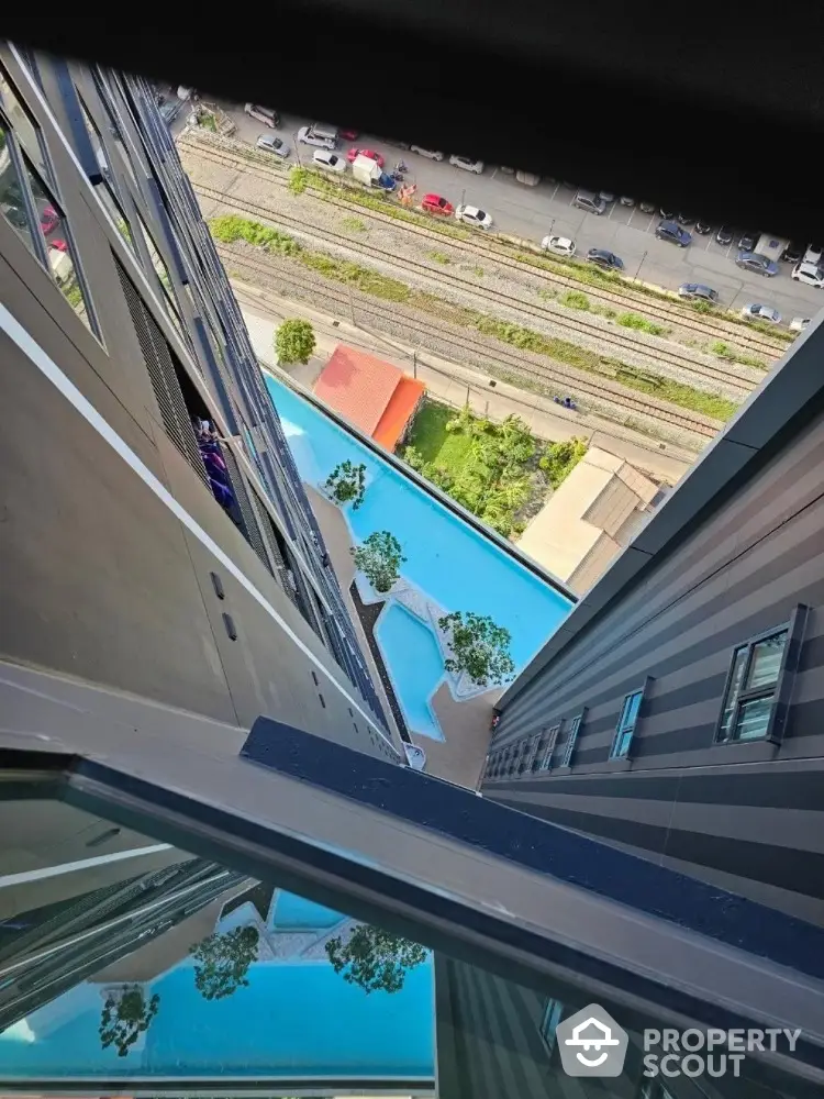 Stunning aerial view of modern apartment building with luxurious pool and cityscape.