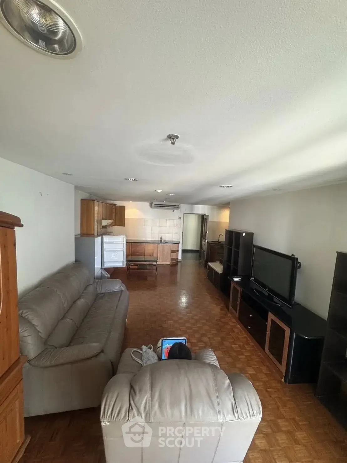 Spacious living room with parquet flooring, cozy seating, and modern entertainment setup.