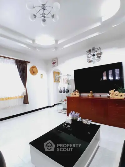 Spacious living room with modern decor and large TV, perfect for relaxation and entertainment.