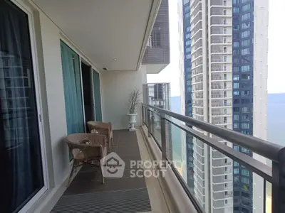 Luxurious high-rise balcony with stunning ocean view and modern seating area.