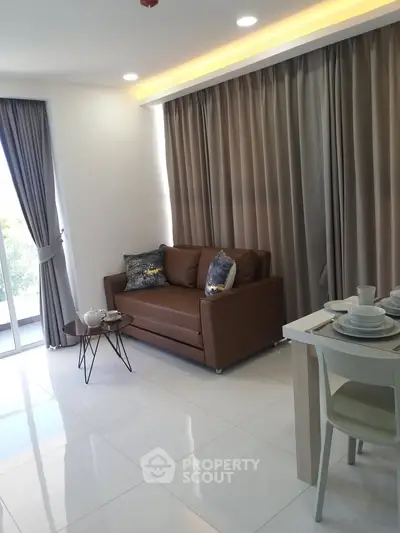 Modern living room with sleek sofa and dining area, featuring elegant curtains and natural light.