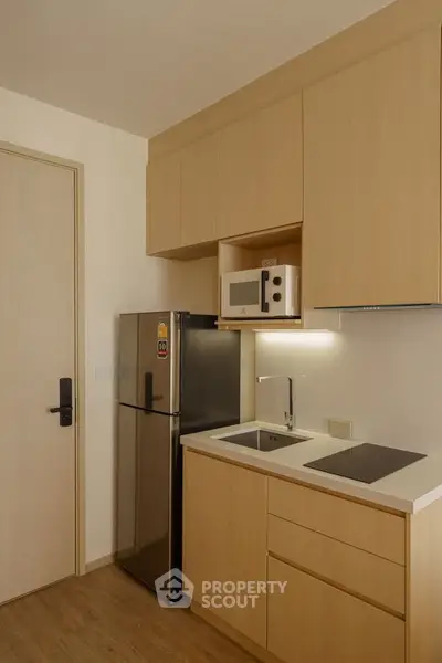 Modern compact kitchen with sleek cabinetry and integrated appliances in a stylish apartment.