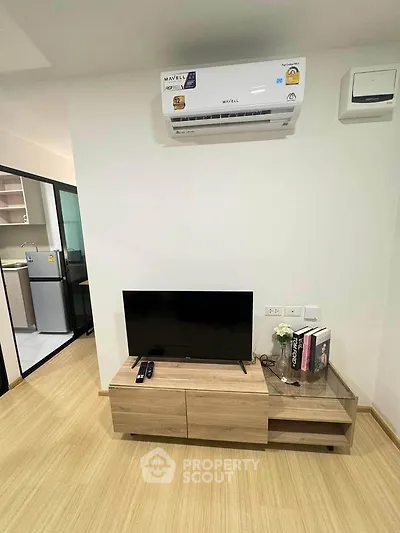 Modern living room with air conditioning and TV unit, adjacent to a sleek kitchen.