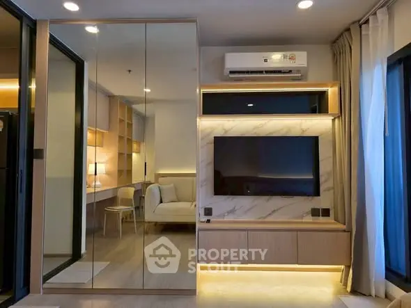 Modern living room with sleek design, featuring a wall-mounted TV, mirrored closet, and ambient lighting.