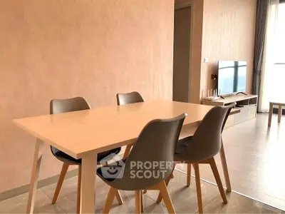 Modern dining area with sleek table and chairs, adjacent to a cozy living room with a TV setup.