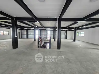 Spacious industrial-style open floor plan with modern steel beams and large windows.