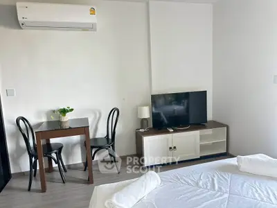 Cozy bedroom with modern furnishings, featuring a TV and dining area, perfect for urban living.