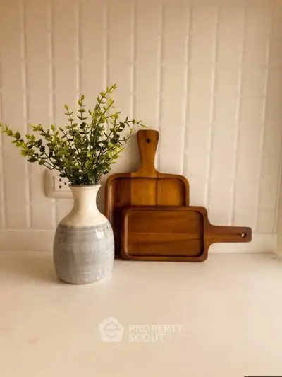 Elegant kitchen decor with wooden cutting boards and a stylish vase on a white countertop.