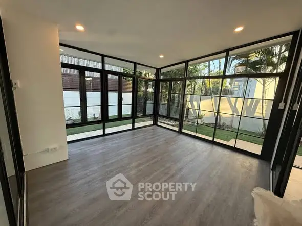 Spacious modern living room with large windows and garden view, perfect for natural light lovers.