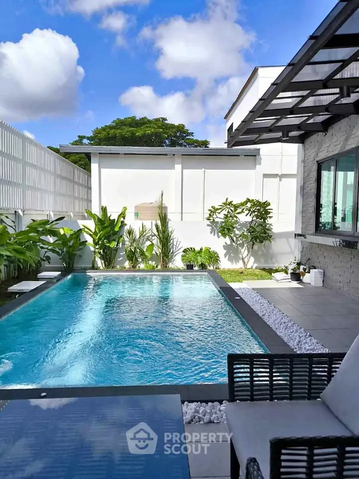 Stunning modern backyard with a sparkling pool and lush greenery, perfect for relaxation and entertainment.