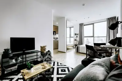 Modern living room with stylish decor and open layout leading to bedroom and kitchen.
