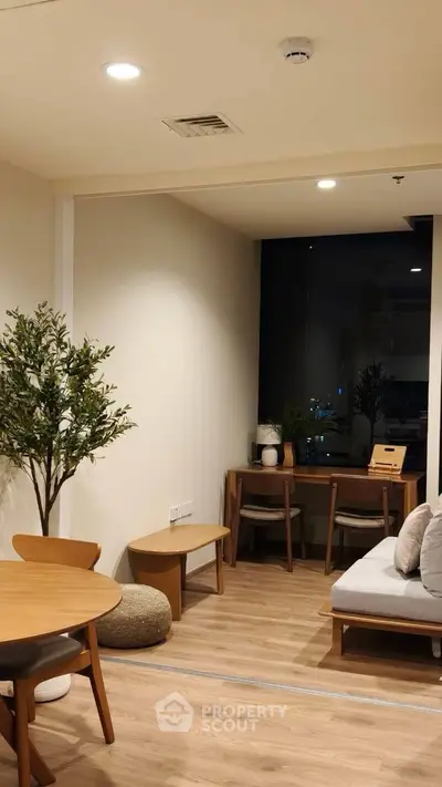 Modern living room with stylish furniture and large window offering city view.