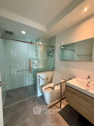 Modern bathroom with glass shower and sleek vanity in contemporary apartment.