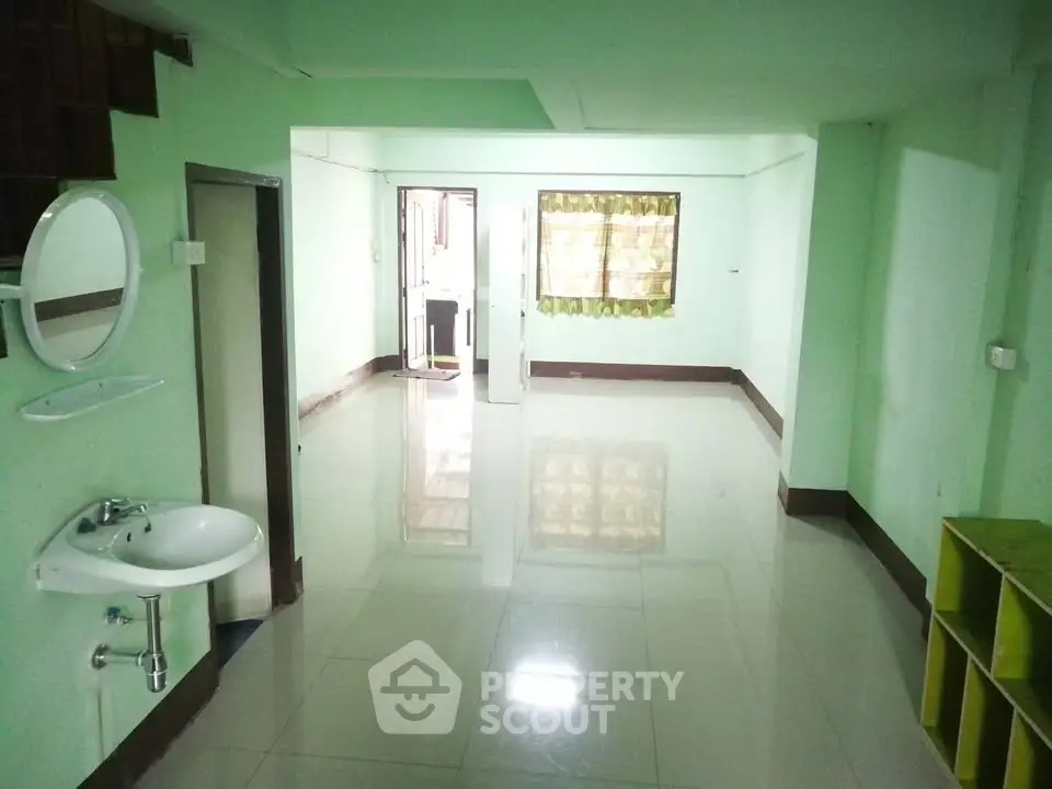 Spacious open-plan living area with glossy tiled floors and a wall-mounted sink, perfect for modern living.