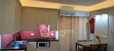 Charming kitchen with red mosaic backsplash and cozy dining area, perfect for modern living.