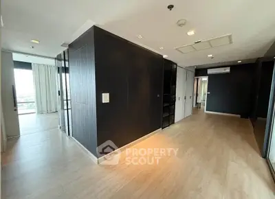 Spacious modern apartment interior with sleek black walls and light wood flooring, featuring an open layout.