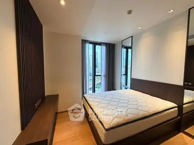 Modern bedroom with large windows and city view, featuring sleek wooden accents and a comfortable mattress.