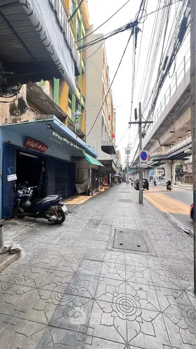 Urban street view with buildings and overhead cables, showcasing city life.